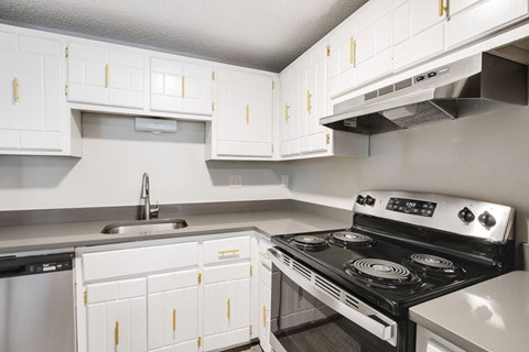 a kitchen with white cabinets and a stove and a sink